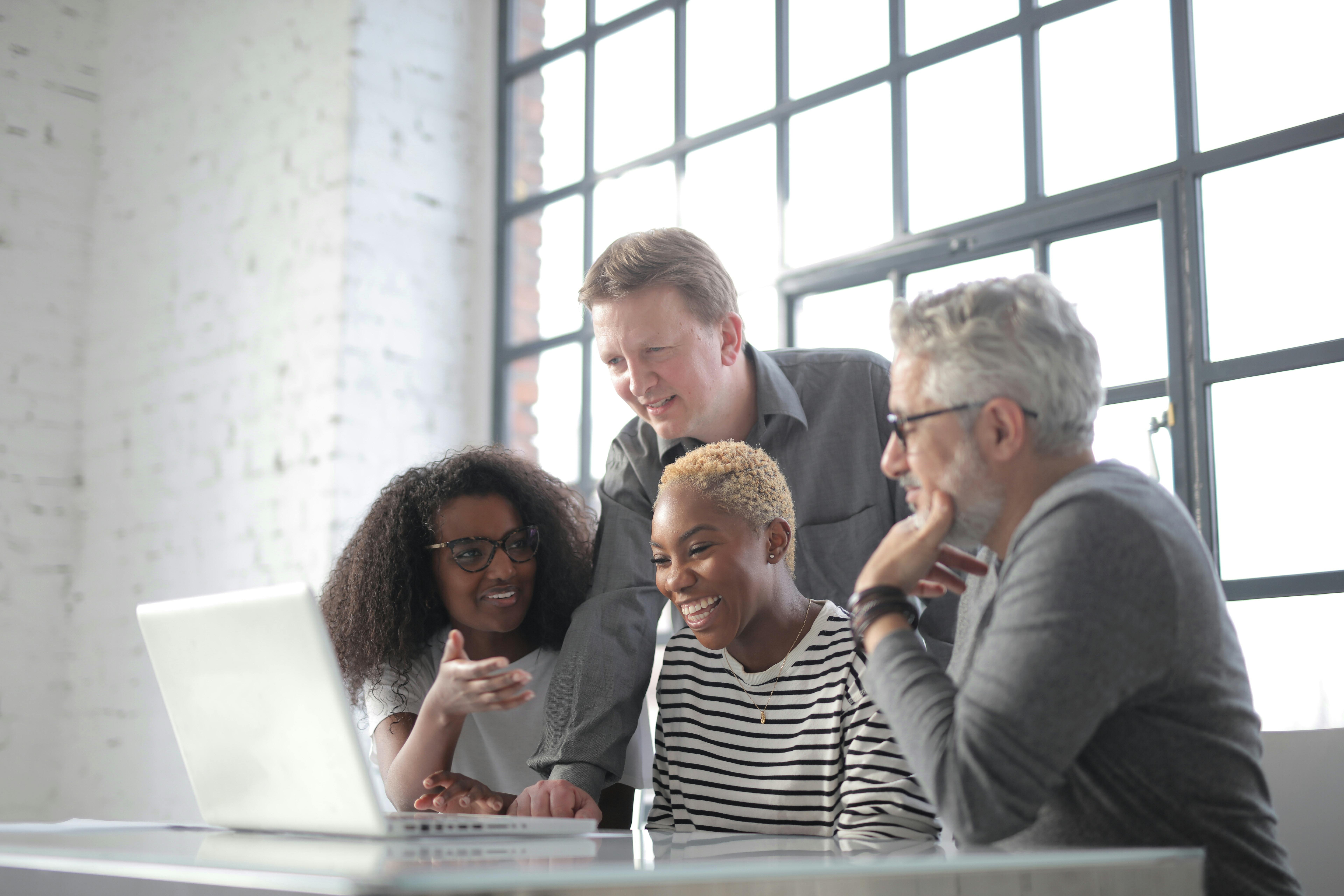 A mixed-age group of adults collaborating around a laptop